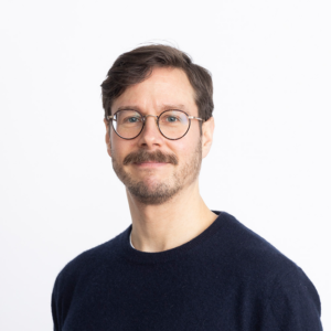 Matti Koskinen, glasses, dark blue shirt, brown hair, moustache.