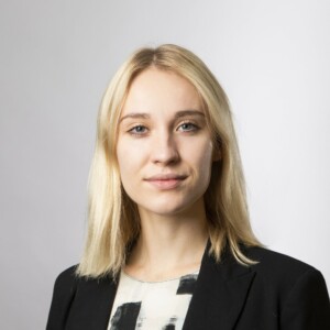 Portrait of Tyyne Karjalainen wearing a black blazer and a black and white T-shirt.