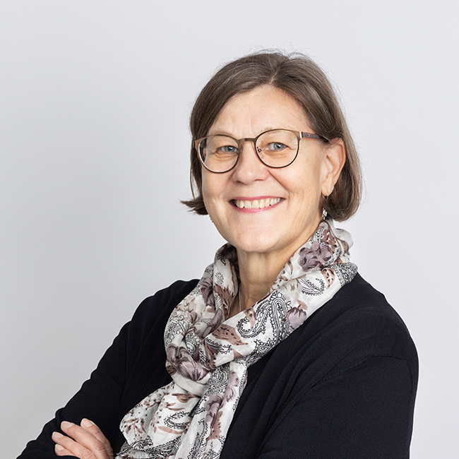 Picture of Mar-Leena Kolehmainen, brown hair, glasses, scarf and black shirt, smiling.