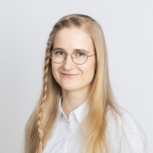 Helmi Räisänen, long blonde hair, big glasses, white shirt, smiling.