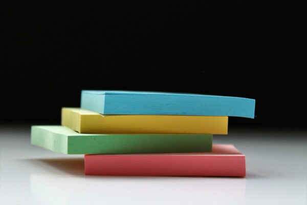 A stack of colourful post-it notes on a white table.