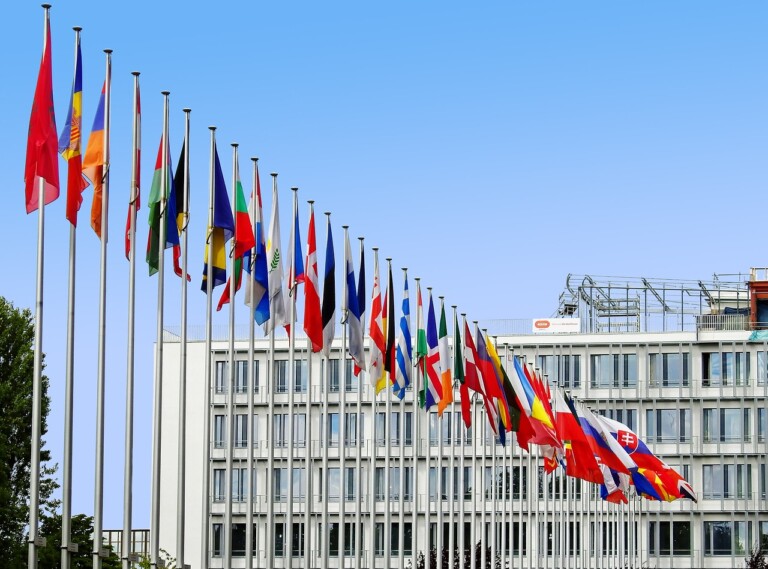 Country flags in front of a white building.