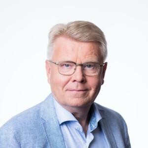 Jani Kokko looking at the camera with a light blue suit on, white background.