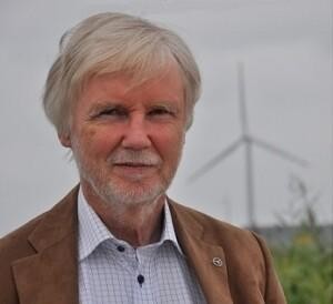 Erkki Tuomioja looking at the camera with a brown suit on, grey sky in the background.