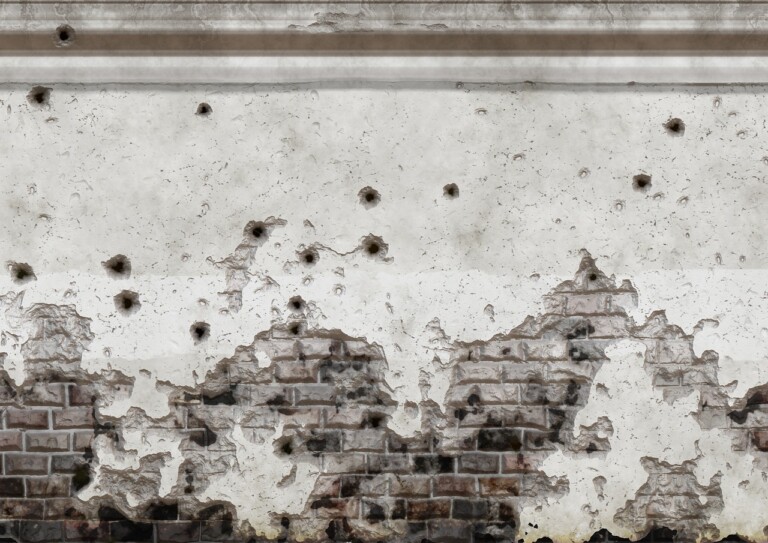 Deteriorated white wall and bullet holes in it.