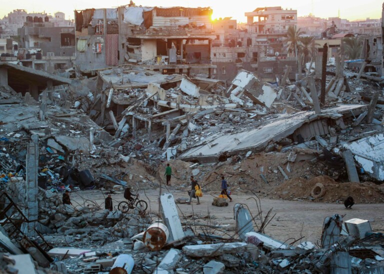 TOPSHOT - Palestinians walk in a devastated neighbourhood due to Israeli strikes in the southern Gaza Strip city of Khan Yunis on December 2, 2024, amid the ongoing war between Israel and the Palestinian Hamas movement.