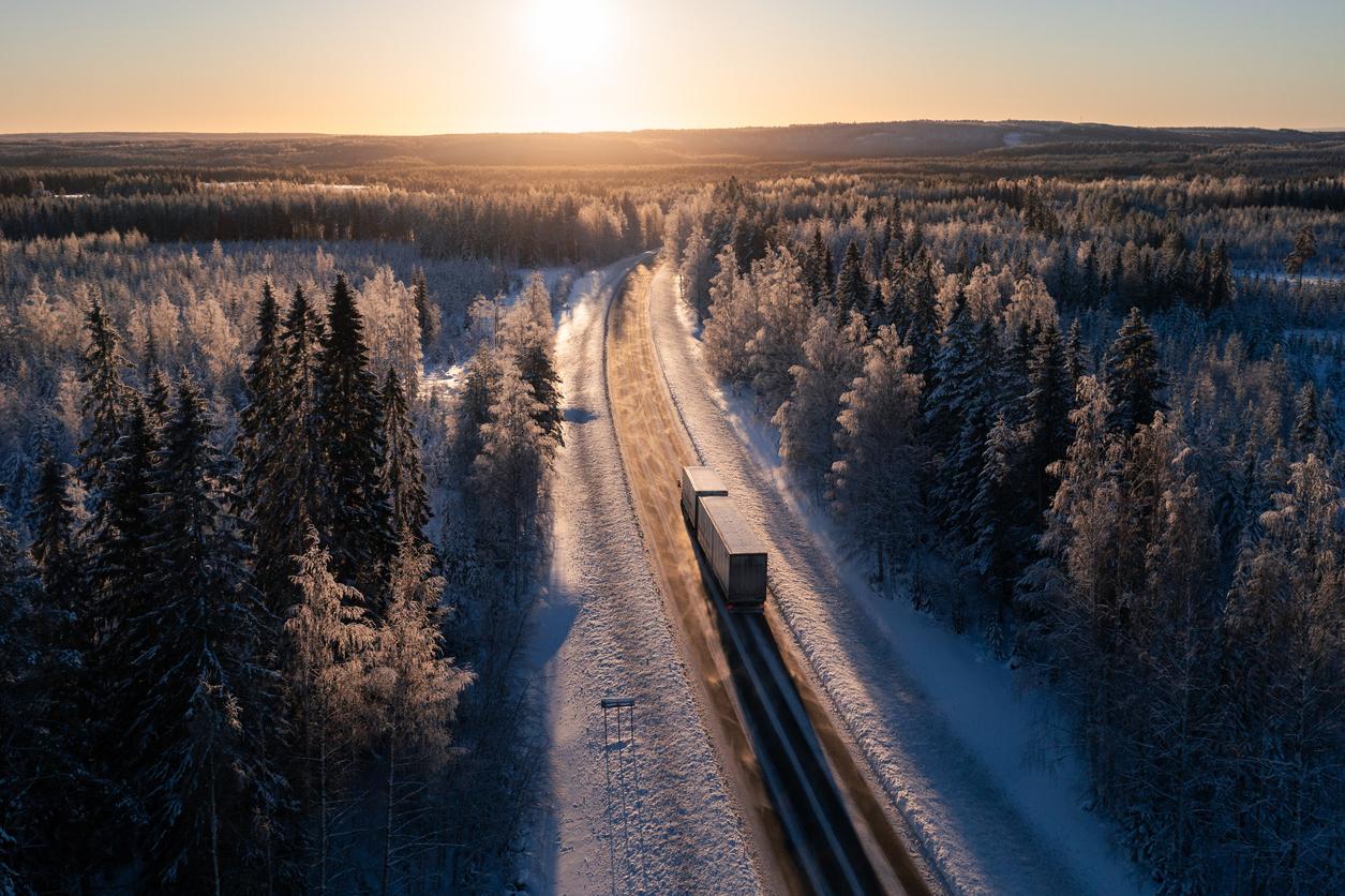 Cargo truck on a highway in winter landscape against sunset. Delivery and transportation in Northern Europe.