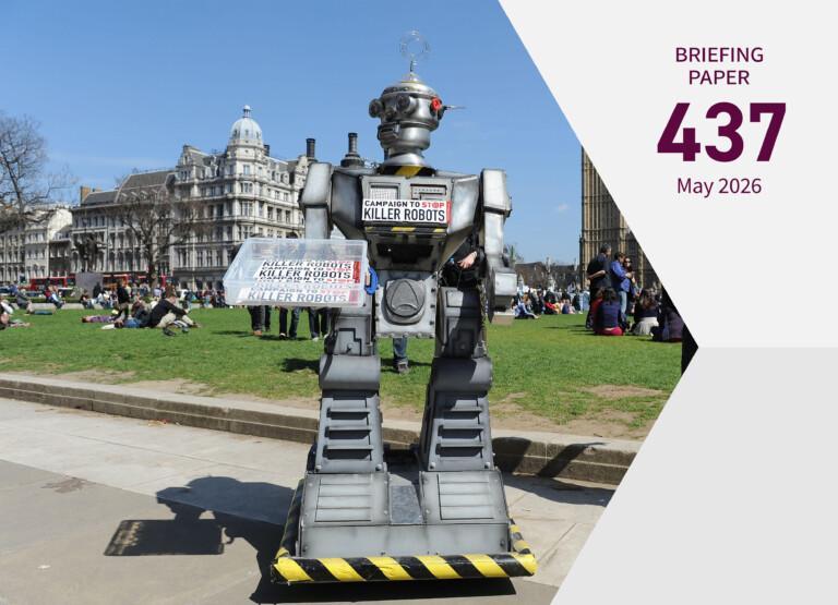 Cover of the publication; a robot figure standing outside in a park with people and buildings in the background. The robot is holding a sign with the text "Campaign to stop killer robots".