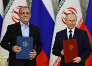Russian President Vladimir Putin and Iranian President Masoud Pezeshkian stand before the flags of Russia and Iran, each holding a folder.
