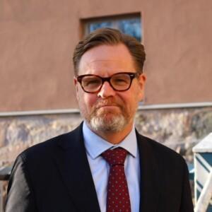 Janne Kuusela in a suit in front of a stone building.